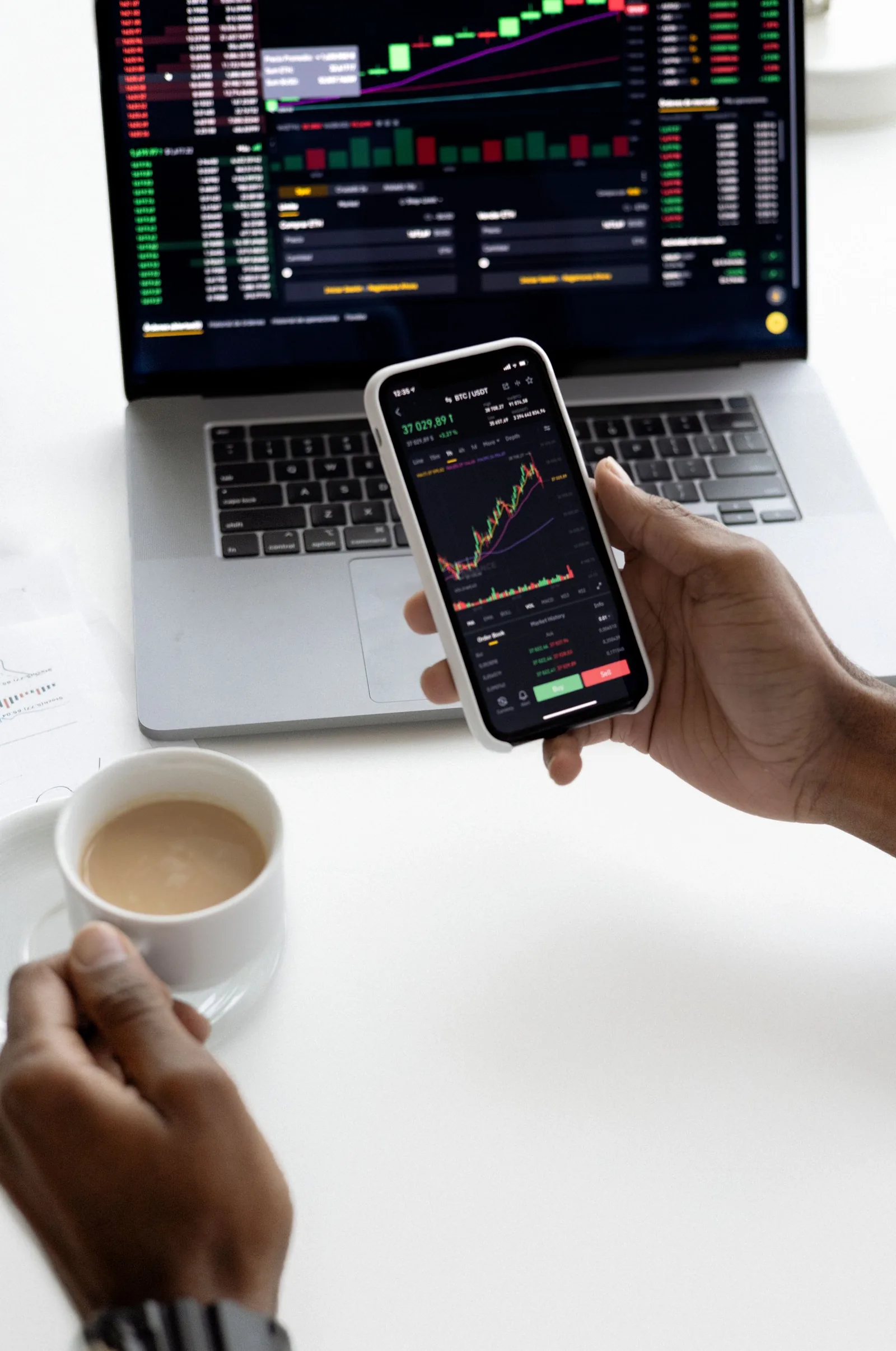 Investor reviewing market information on a phone and laptop